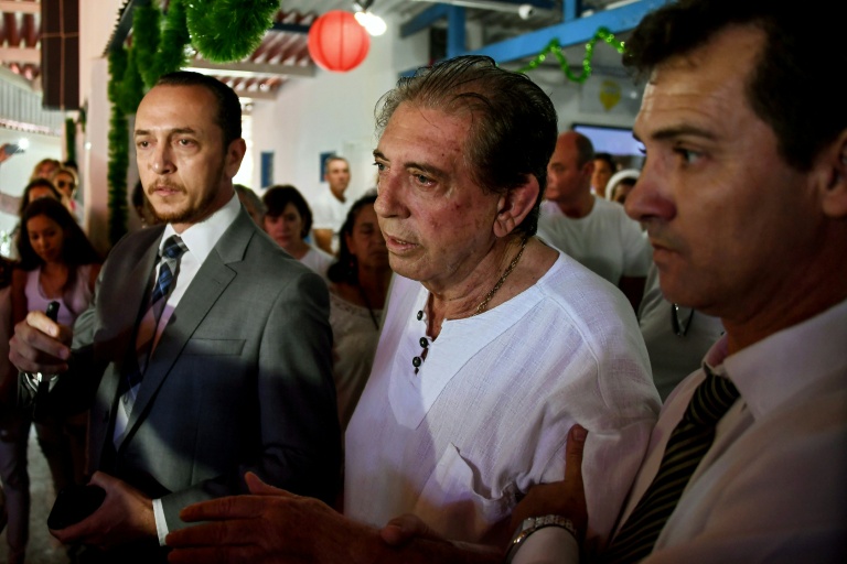 João Teixeira de Faria (C), conhecido como 'João de Deus', é escoltado por seus seguidores - AFP João Teixeira de Faria (C), conhecido como 'João de Deus', é escoltado por seus seguidores - AFP